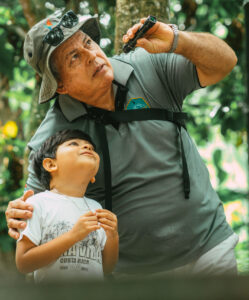 Tour guide showing kids wildlife during a family sloth tour in Costa Rica.